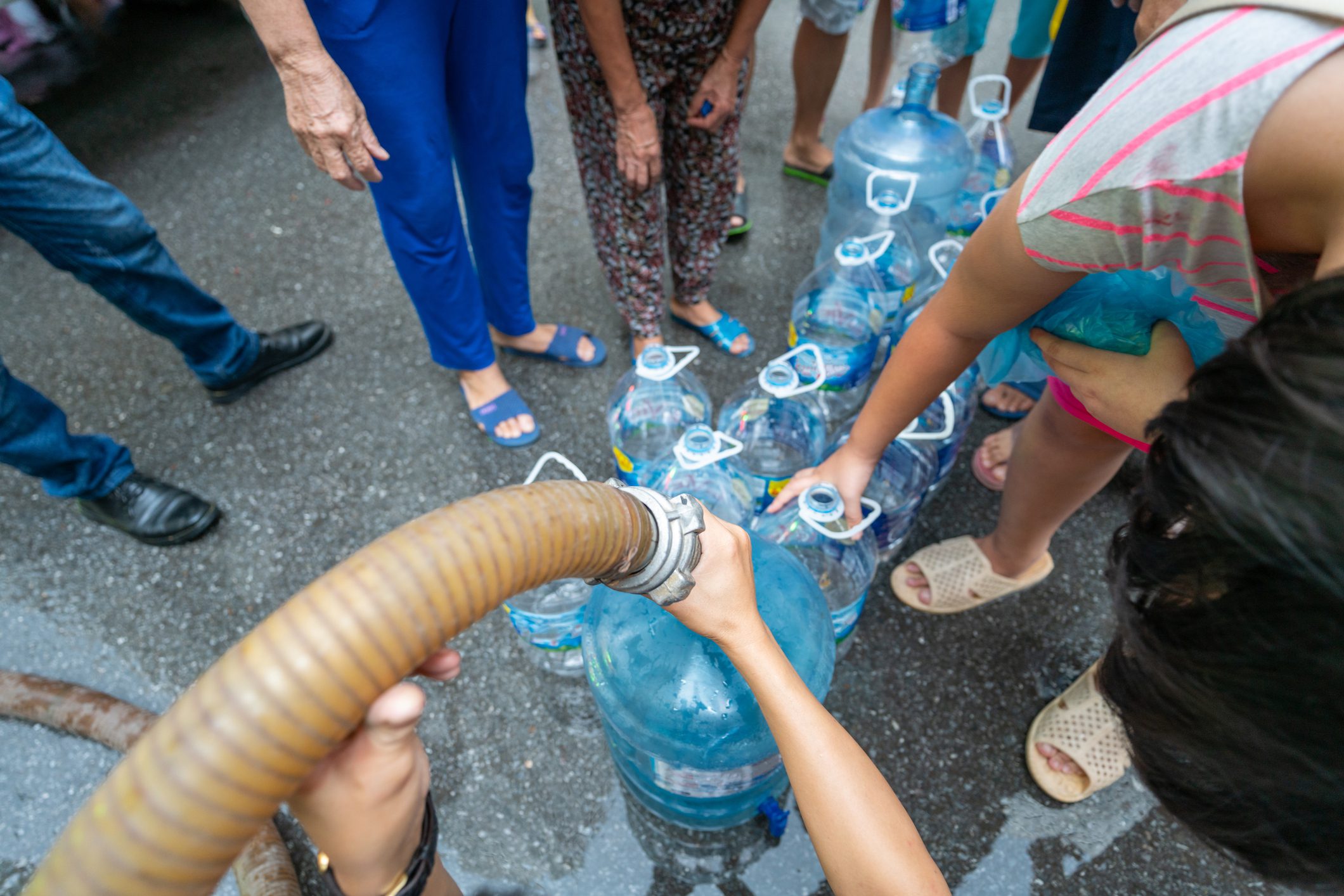 People filling water bottles in street